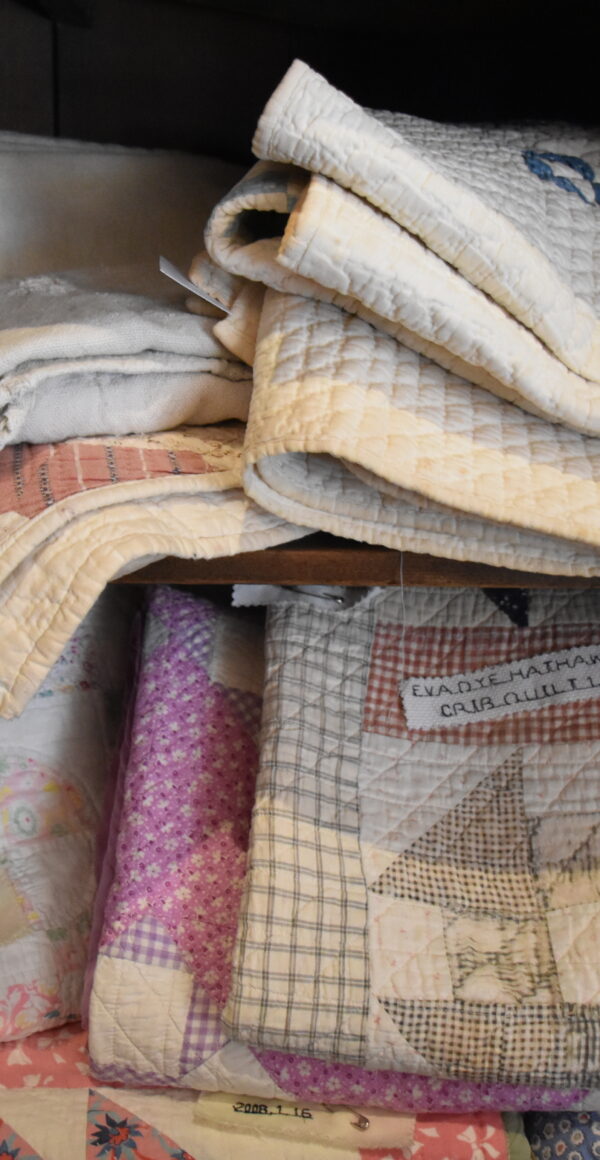Color photo of a stack of antique quilts.