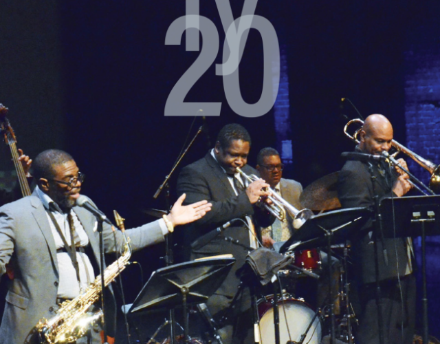 A group of jazz musicians stand onstage - brass in front with a drum kit and percussionist seated in back. At the top of the image, the words Mid Atlantic Arts Annual Report FY20 are printed.