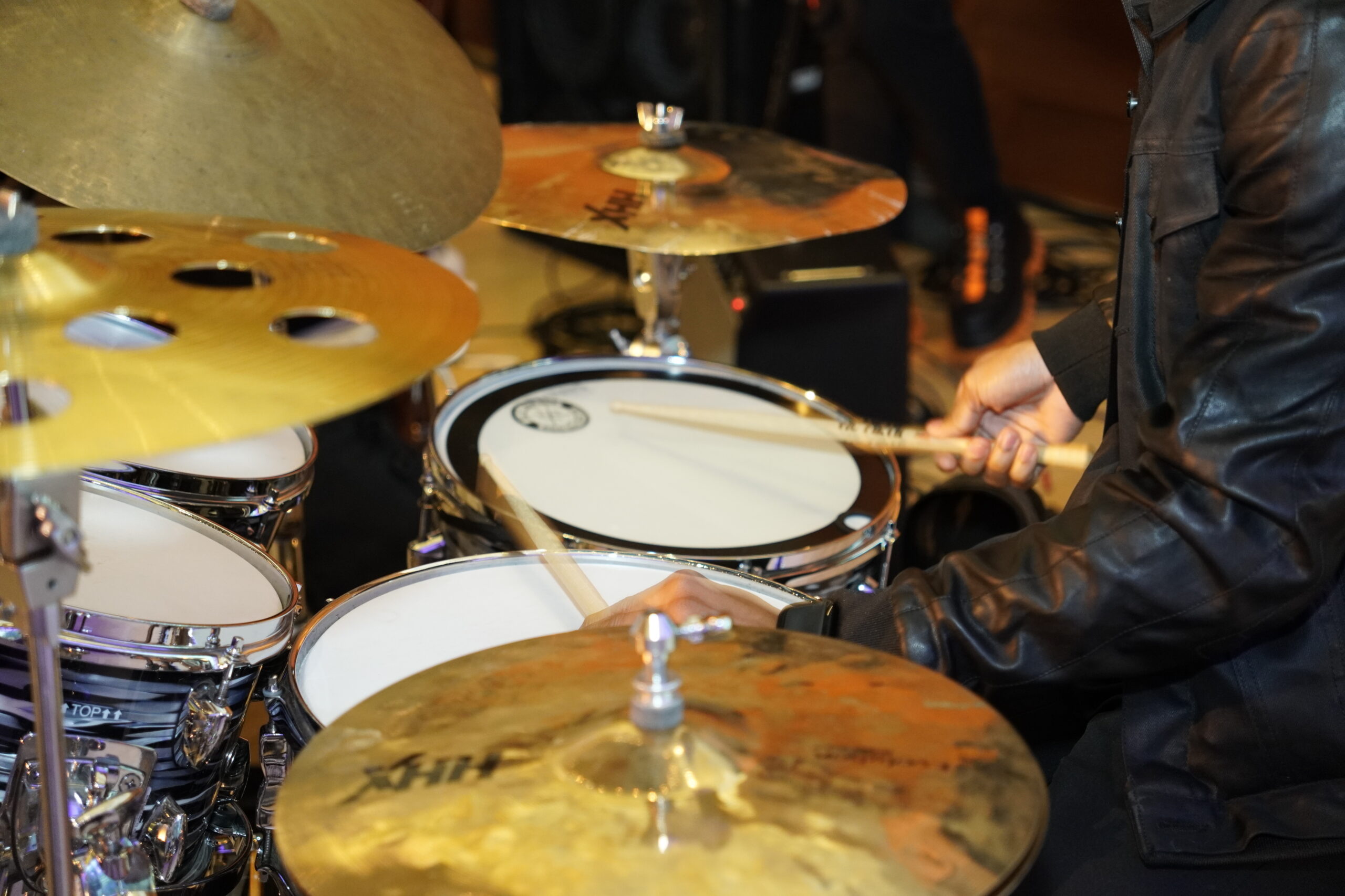 Close up color photo of a drummer playing a drum kit.