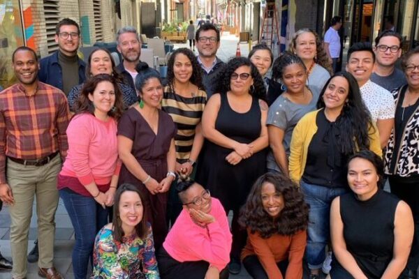 A large group of people kneel and pose for a photo on a pedestrian street.