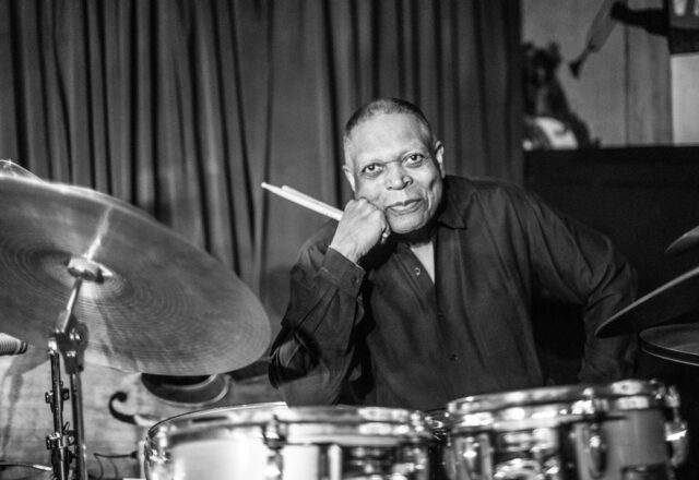 Black and white image of Billy Hart behind a drum kit.