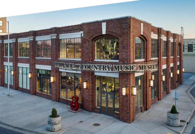 Color photo of the Birthplace of Country Music Museum. The Museum is a two-story red brick building with large square windows.