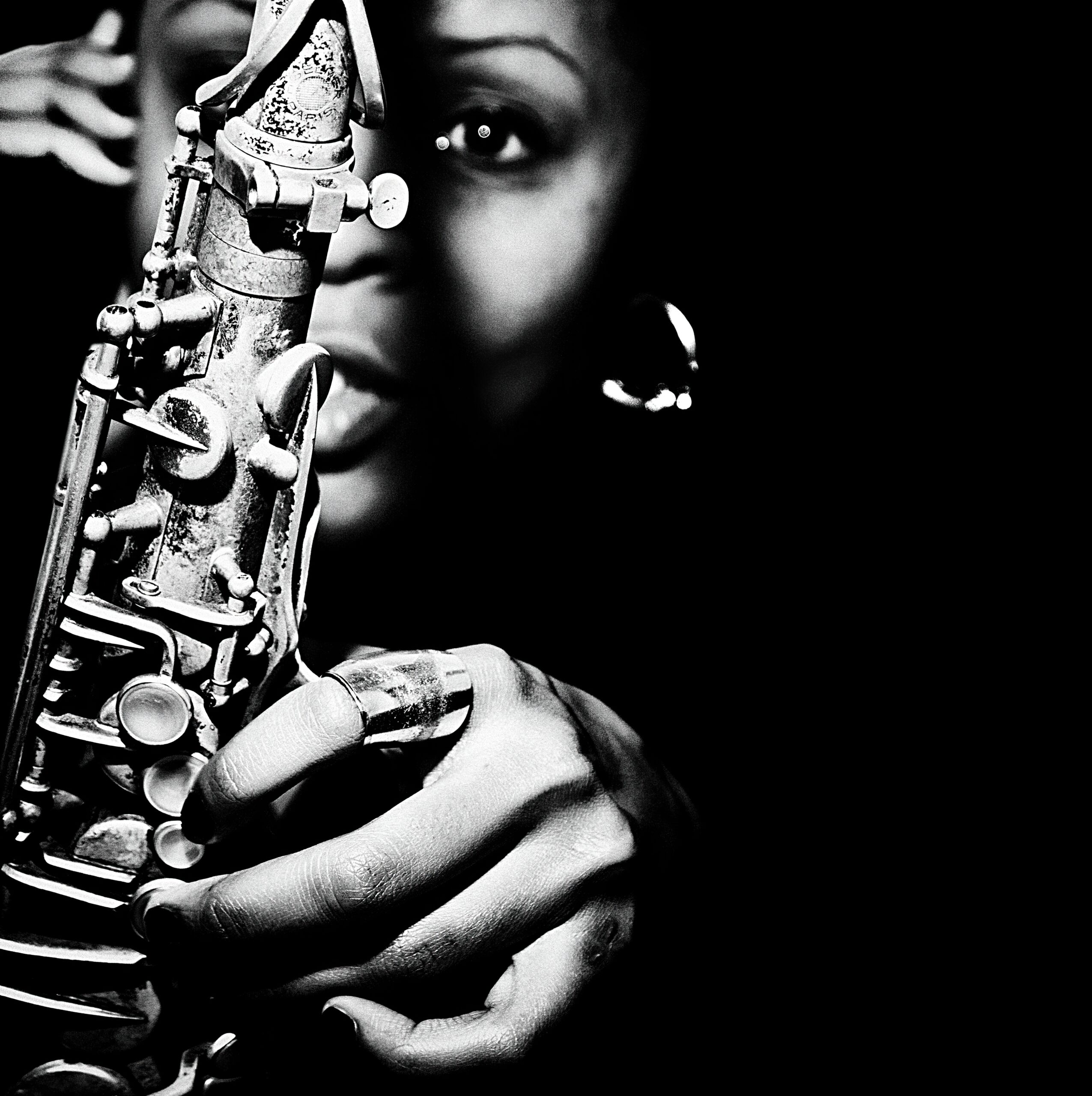Black and white image of Matana Roberts holding a woodwind instrument in front of her face.