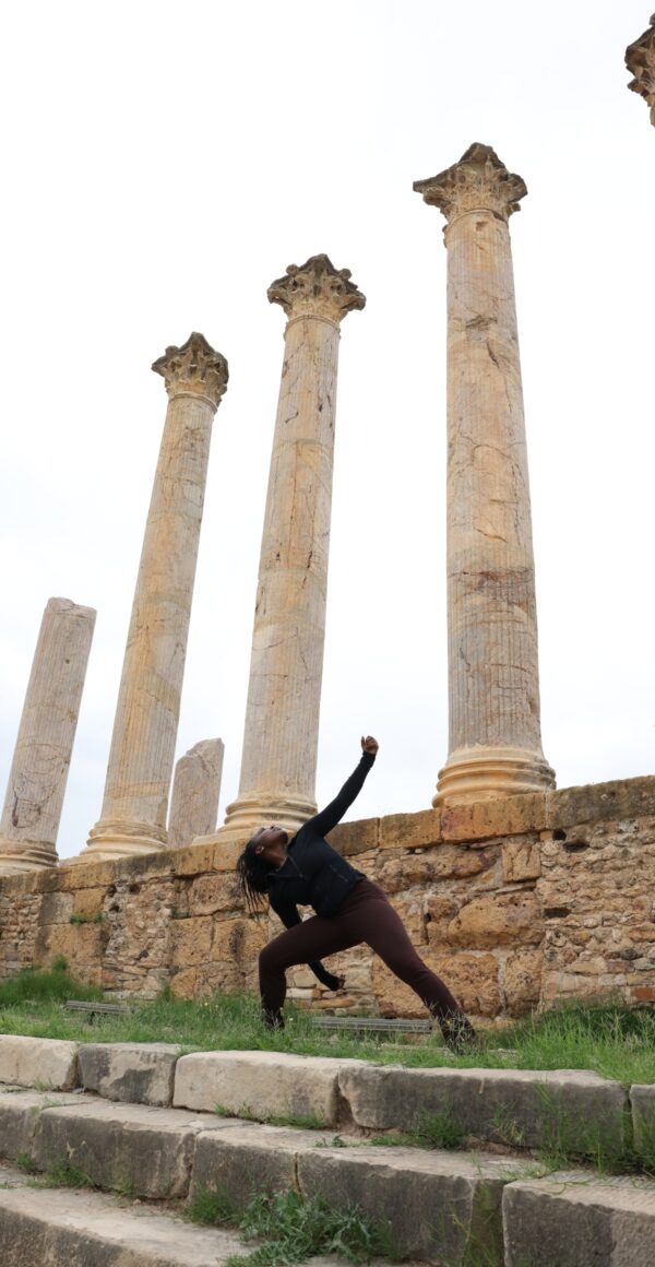 Color image of a lone dancer striking a pose in front of ancient columns.