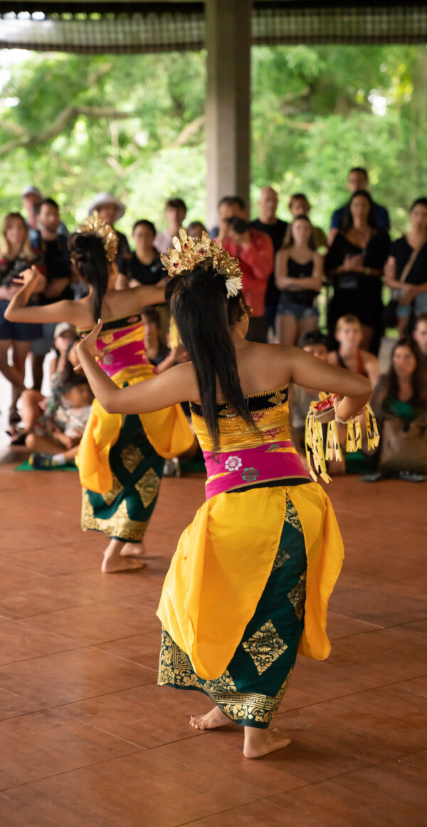 Color photo of two traditional dancers performing in a tent for a crowd of folks.