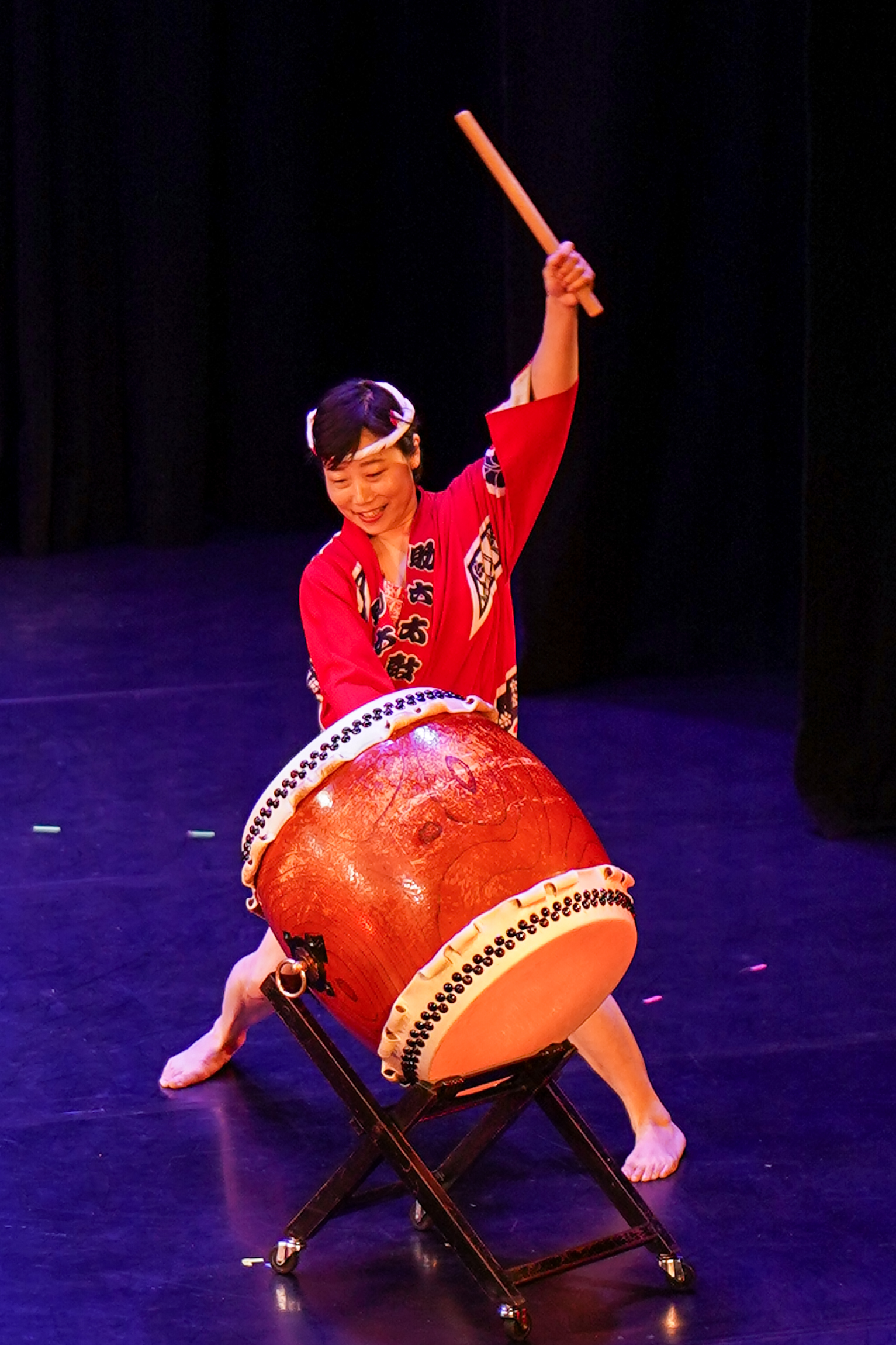 A drummer dressed in traditional Japanese costume, plays a taiko drum.