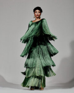 Color photo of Luedji Luna. The artist wears a long forest green dress made up of long tiered fringe.