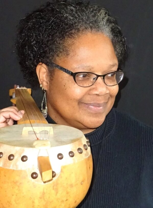 Dr. Dena Jennings headshot. She holds a traditional African stringed instrument.