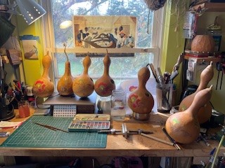 Partially painted gourds at a table in front of a window.