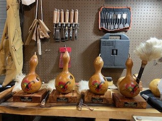 Finished gourd awards and cow tail switches on a work bench.