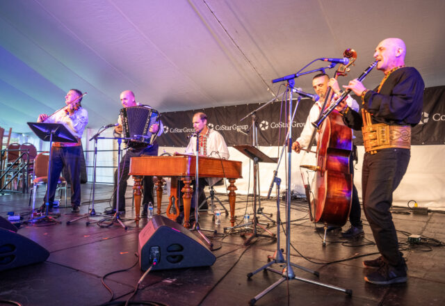 A band plays outside on a festival stage.