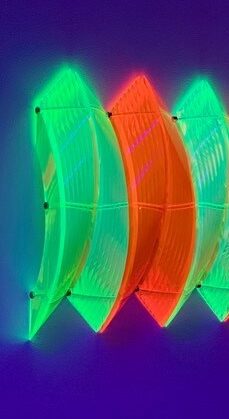 Color photo of vibrant orange and green half screw sculpture without a head on a deep blue background.