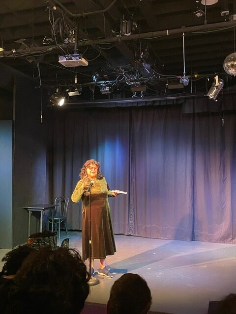Jill Clause tells a story while at a standing microphone.