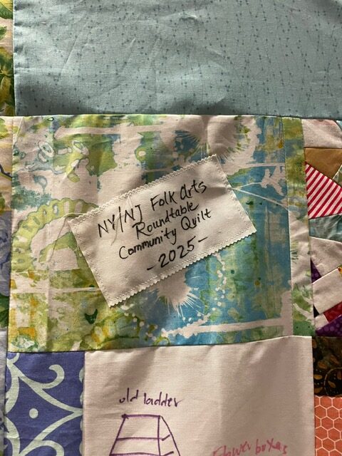 Close up of quilt with label that says NY NJ Folk Arts Roundtable Community Quilt 2025.