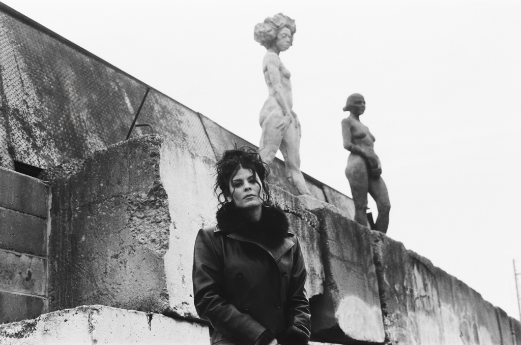 Black and white shot of Gabrielle Cavassa standing in front of a stone wall with statuary.