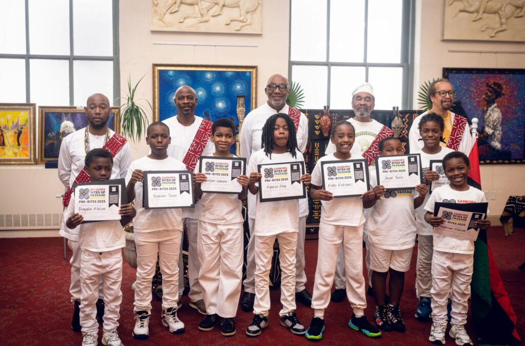 A group of youth stand in a line proudly holding award certificates. A group of adults stand behind them.