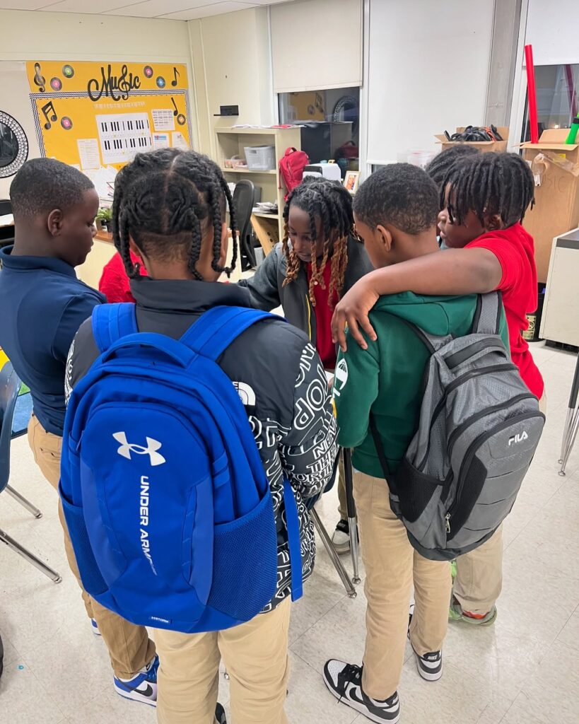 A group of youth gather in a circle in a classroom.