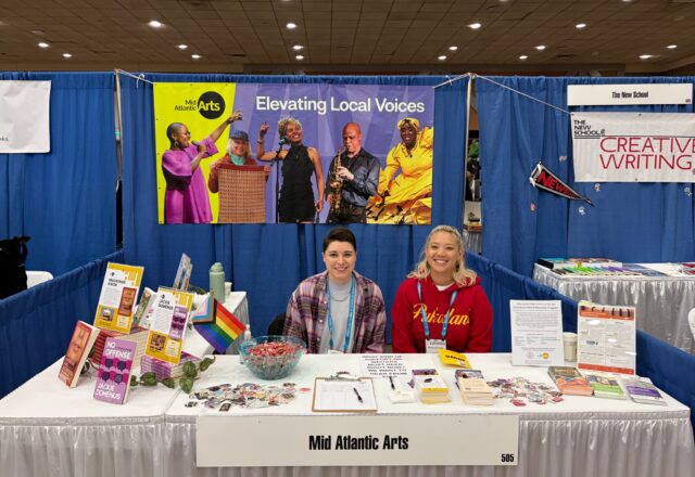 Two people sit at a brightly colored conference booth ready to meet conference goers.