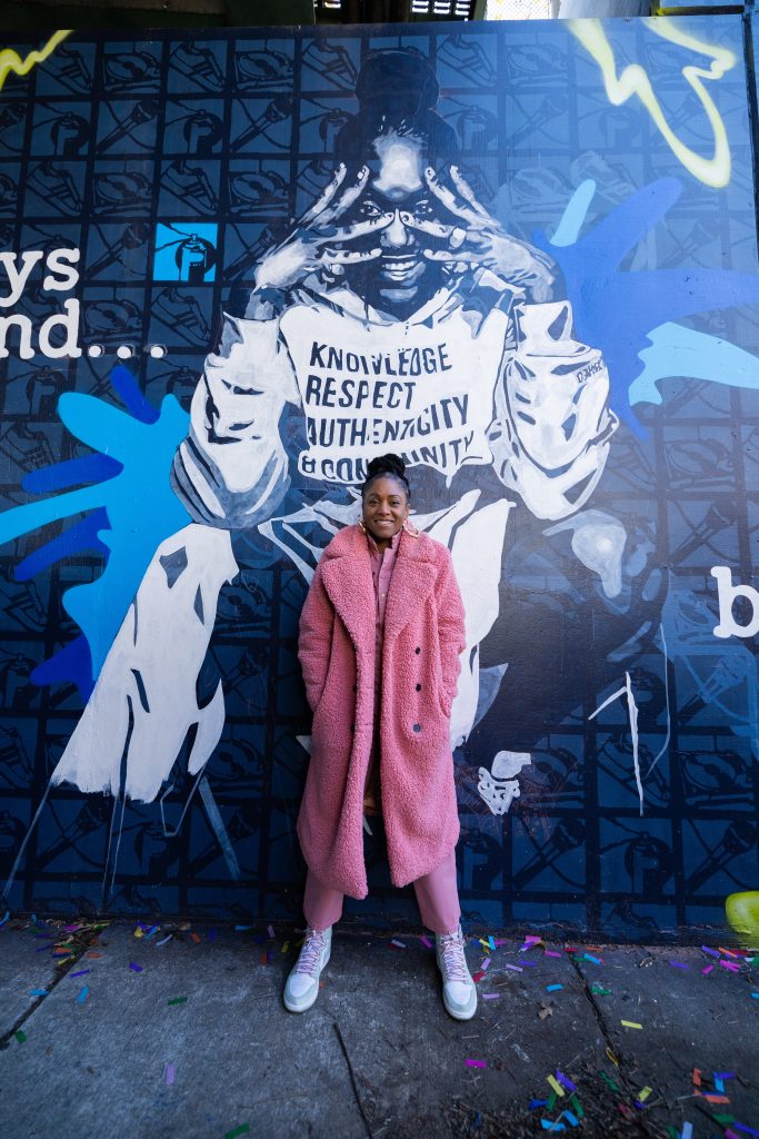 Michele Byrd-McPhee stands in front of a mural of herself.