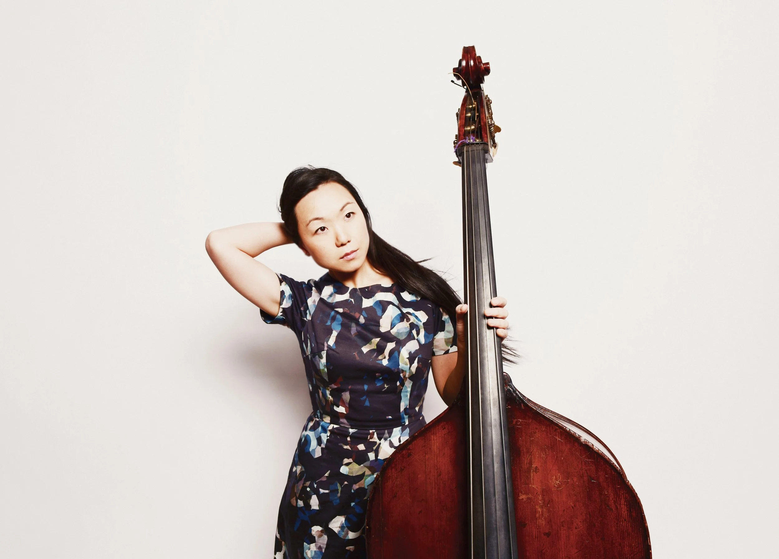 Linda poses in a studio with a bass beside them.